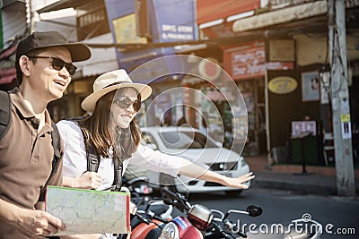 Asian backpack couple tourist standing near to the road waiting for local taxi Stock Photo