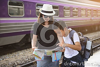 Asian backpack traveler mother with son using generic local map at a train station Stock Photo