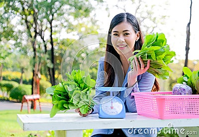 Asian beautiful business girl sit and hold the vegetable to present green product concept Stock Photo