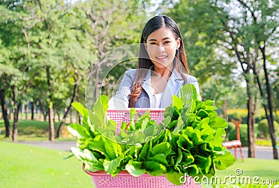 Asian beautiful business woman show the basket of vegetable and present in front of her that relate to green business concept Stock Photo