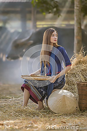 Asian beautiful girl winnowing rice separate between rice and rice husk Stock Photo