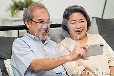 Asian beautiful old woman and senior man couple in love using mobile phone for video call with son, daughter and talking to grandc Stock Photo