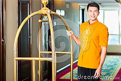 Asian bell boy or porter bringing suitcase to hotel room Stock Photo