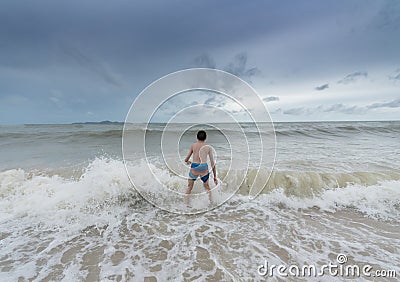 An Asian boy has felt happy and fun on the beach with a cloudy sky Stock Photo