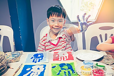 Asian boy smiling and showing hands in paint. Pop art style. Stock Photo