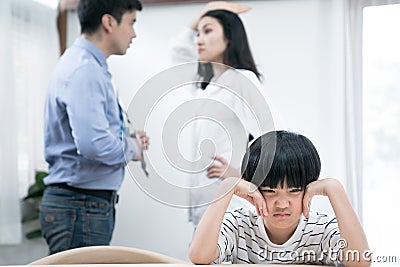 An Asian boy uses his hands to cover his ears because he doesn`t want to hear the parents quarrel. Stock Photo