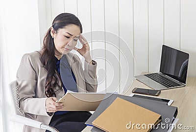 Asian business woman with headache at office , Tired accountant with paper folders in office, feeling sick at work Stock Photo
