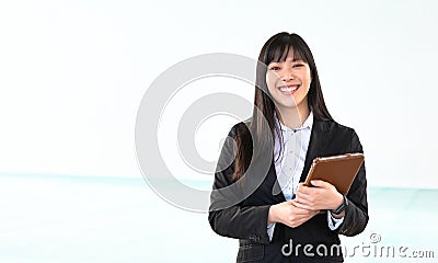 Asian business woman holding smart mobile tablet in office - Young smiling Chinese girl ready for working on digital marketing Stock Photo