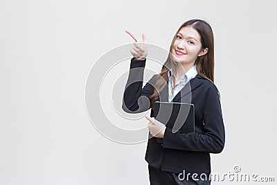 Asian business working woman in black suit smiles happily while she holds tablet and shows point up to present something on white Stock Photo