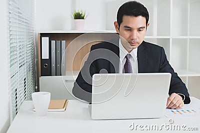 Asian businessman concentrating on using laptop computer Stock Photo