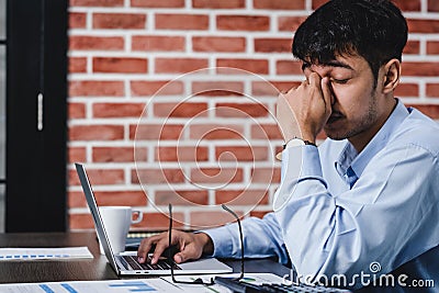 Asian businessman get stress and headache when working with laptop on desk at modern office.business fail concept.man caught eye Stock Photo