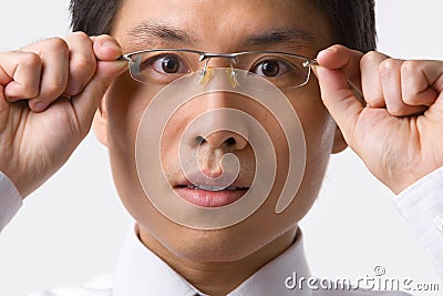 Asian businessman holding glasses to camera Stock Photo