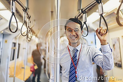 An Asian businessman is traveling a public train. Stock Photo