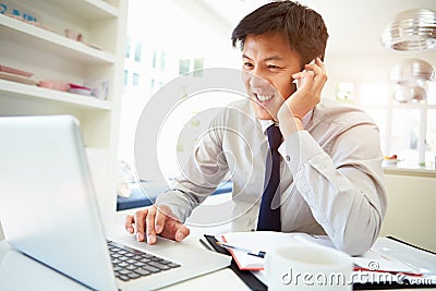 Asian Businessman Working From Home Using Mobile Phone Stock Photo