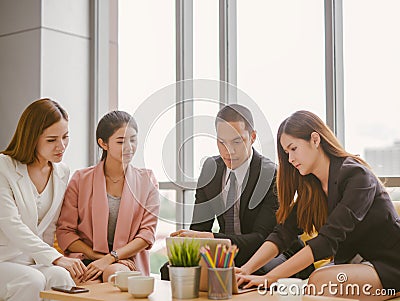 Asian businessmen and businesswoman discussing work sitting at conference table in office. Stock Photo