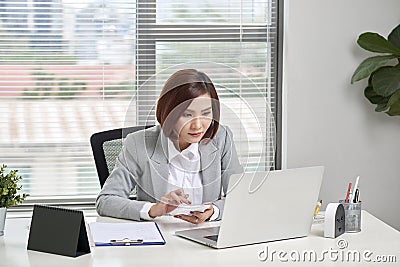 Asian businesswoman or accountant working pointing graph discussion and analysis data charts and graphs and using a calculator to Stock Photo