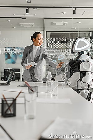 Asian businesswoman operating robot while holding Stock Photo