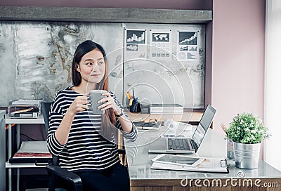 Asian businesswoman take a coffee break after working with smiling face,Happy office life concept,working woman at modern home Stock Photo