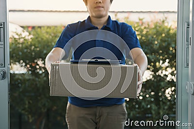 Asian cargo carrier holds a cardboard box with the package inside and the recipient is signing the package Stock Photo