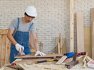 Asian carpenter use a sander machine to smooth plywood surfaces Stock Photo