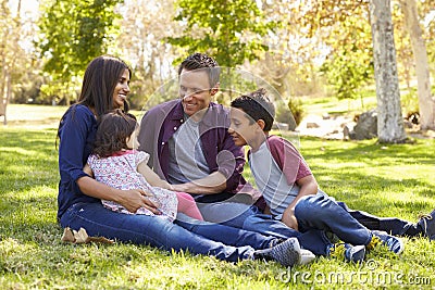 Asian Caucasian mixed race family sitting on grass in a park Stock Photo