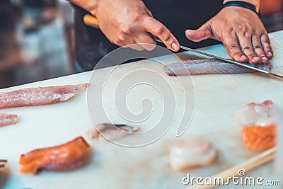 Asian Chef slicing raw fish on chopping board, cooking sushi menu. Japanese famous traditional food, seafood, street food concept Stock Photo