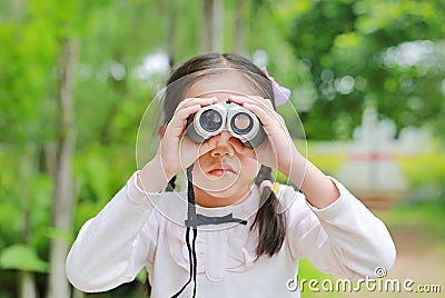 Asian child girl with binoculars in nature fields. Explore and adventure concept Stock Photo