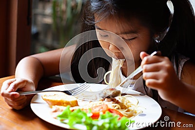 Asian child girl eating delicious Spaghetti Carbonara Stock Photo