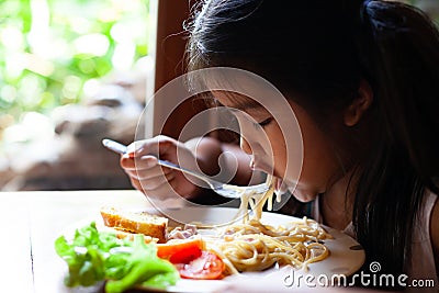 Asian child girl eating delicious Spaghetti Carbonara Stock Photo