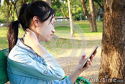 Asian child girl has neck pain,massage her neck,bending head while playing the mobile phone for a long time,stiff neck,muscles Stock Photo