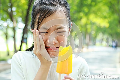 Asian child girl have hypersensitive teeth eating ice-cream,feel painful ,female teenage have sensitive teeth problem with ice- Stock Photo