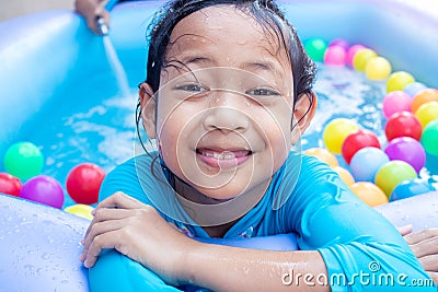 Asian Child Girl Having Fun In Garden Paddling Pool with father fill wather in background Stock Photo
