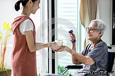 Asian child girl hold a glass of warm milk,taking care of senior woman,giving fresh milk or nutritional supplements in the morning Stock Photo