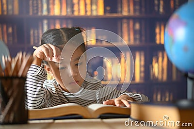 Asian child girl industrious is sitting at a desk indoors. Kid is learning in home Stock Photo