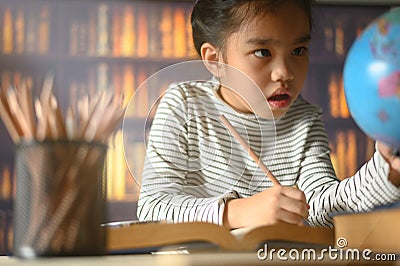 Asian child girl industrious is sitting at a desk indoors. Kid is learning in home Stock Photo