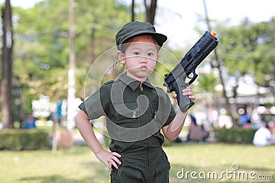 Asian child girl in pilot soldier suit costume with shooting gun up. Dream job concept Stock Photo