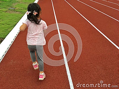 Asian child girl running on red track. Stock Photo