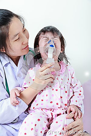 Asian child having respiratory illness helped by health professional with inhaler. Sad girl crying. Stock Photo