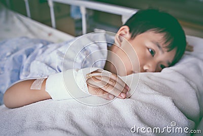 Asian child lying on sickbed, saline intravenous IV on hand. V Stock Photo