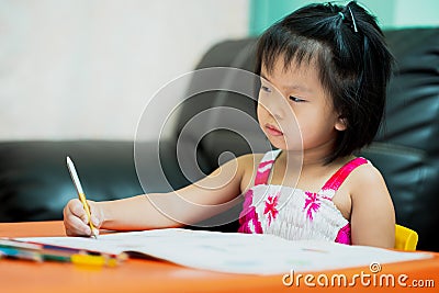 Asian child is sluggish having sleepiness while doing homework. Girl close half eyes. Cute kid aged 4-5 years old Stock Photo