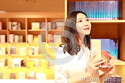 Asian Chinese beautiful pretty young cute woman girl student Teenager read book in bookstore library smile spend her pastime Stock Photo