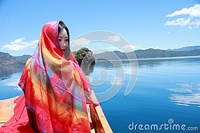 Asian Chinese beauty in red dress with red scraf on head, at Yunnan Lugu lake, enjoy free time Stock Photo