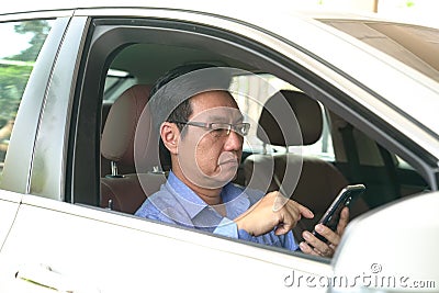 Businessman messaging on his cell phone inside his car Stock Photo