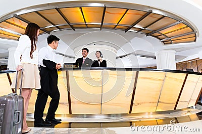 Asian Chinese couple arriving at hotel front desk Stock Photo