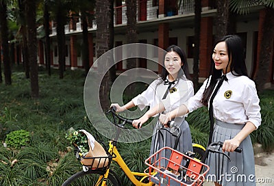 Relax Asian Chinese pretty girls wear student suit in school enjoy free time ride bike in nature spring garden Stock Photo