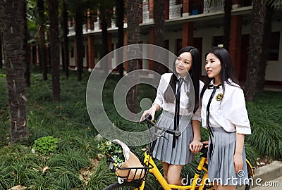 Relax Asian Chinese pretty girls wear student suit in school enjoy free time ride bike in nature spring garden Stock Photo