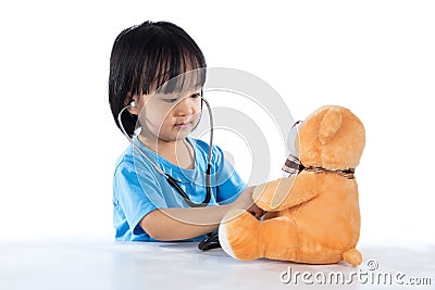 Asian Chinese little doctor girl examine teddy bear Stock Photo