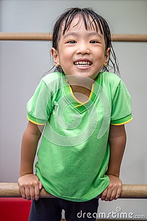 Asian Chinese little girl hanging on uneven bars Stock Photo