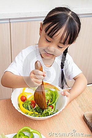 Asian Chinese little girl making salad in the kitchen Stock Photo