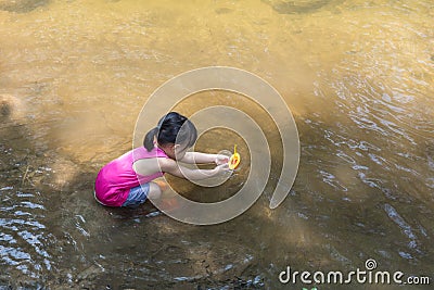 Asian Chinese little girl playing toy boat in the creek Stock Photo